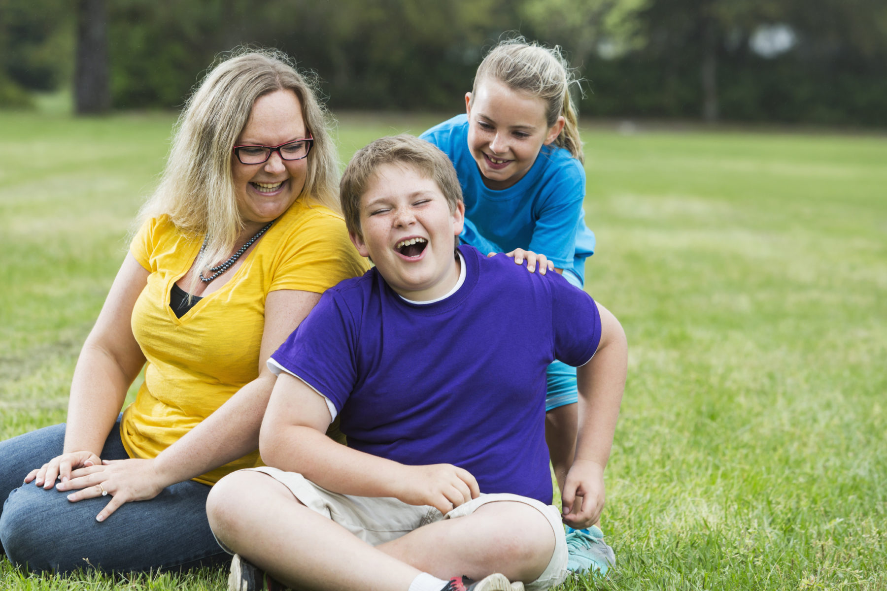 Mother and two children laughing in the park